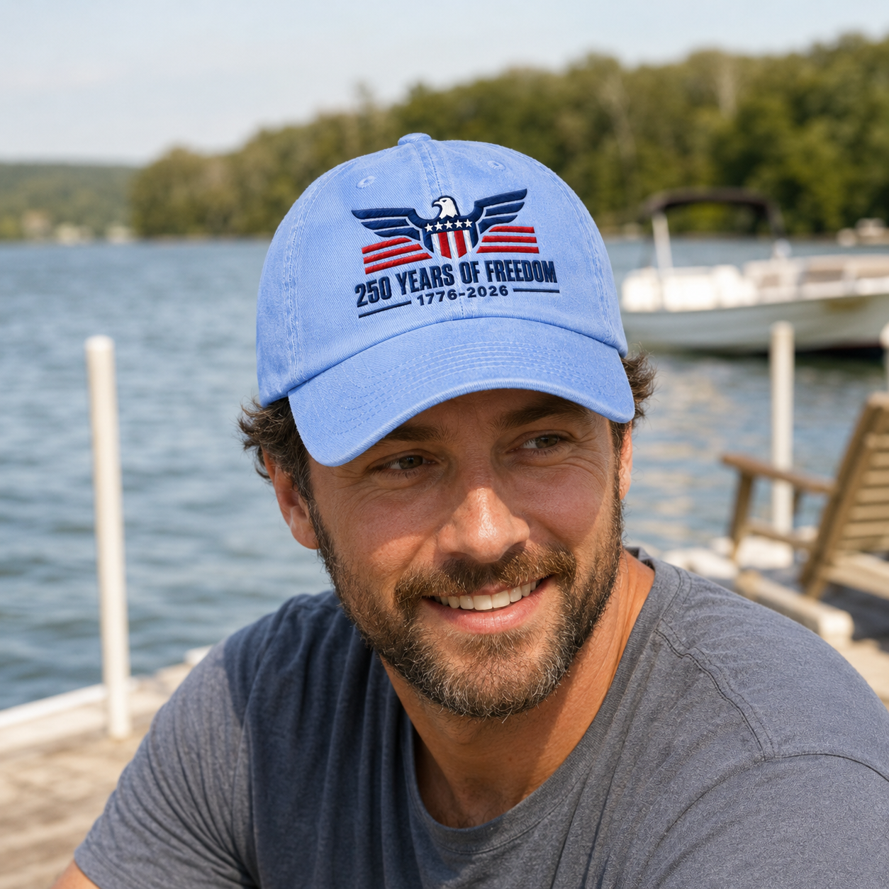 Man smiling by a lake wearing a light blue washed baseball cap with embroidered patriotic freedom design