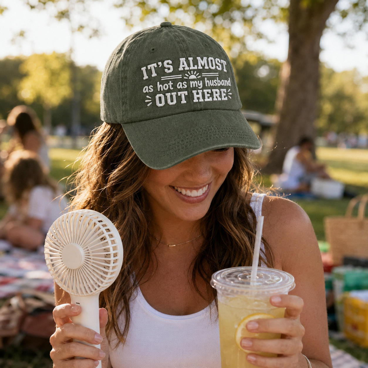 Woman at a picnic wearing an army green washed baseball cap with embroidered funny wife quote