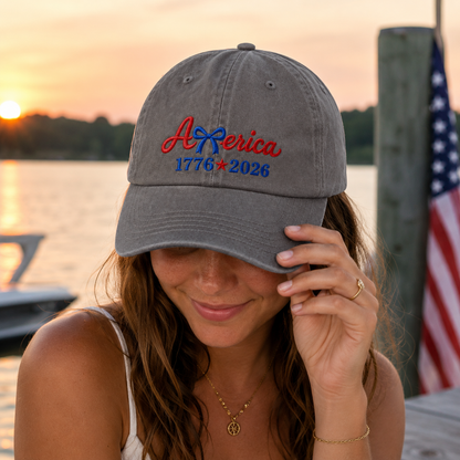 Woman adjusting a grey washed cotton baseball cap with red and blue patriotic America embroidery at sunset