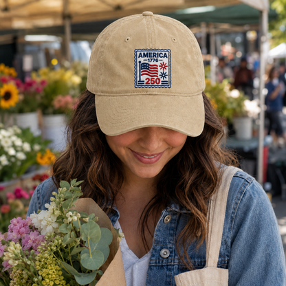 Woman holding flowers at a market wearing a sand washed cotton baseball cap with embroidered patriotic America 250 stamp