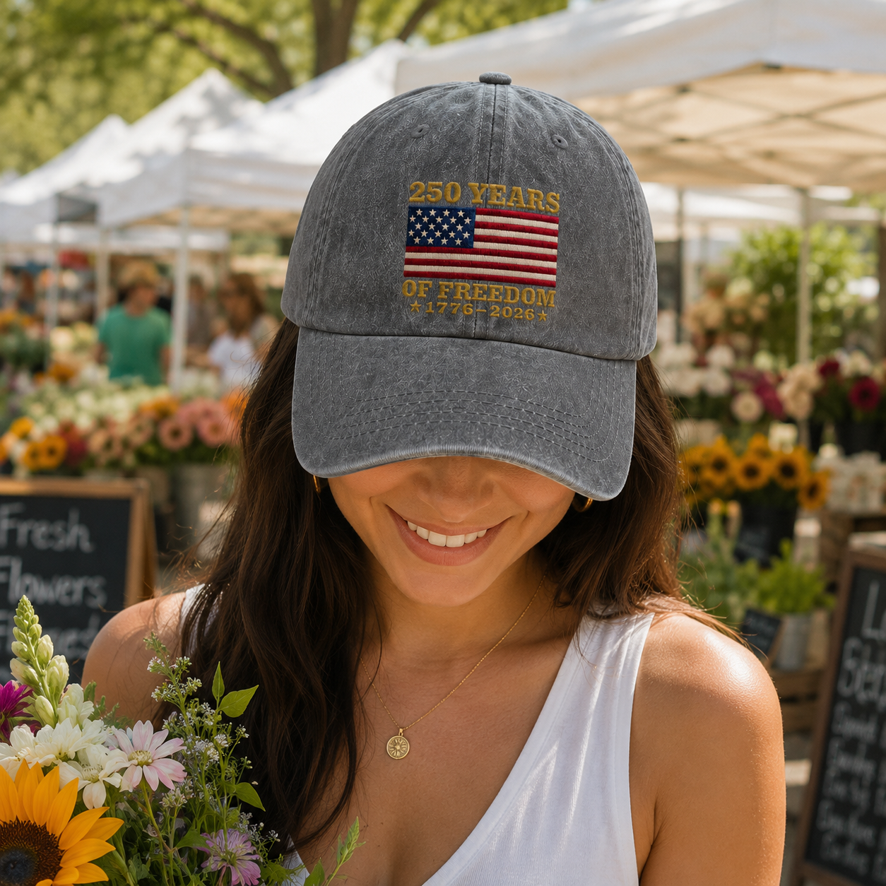 Woman holding a sunflower bouquet at a market wearing a grey washed baseball cap with embroidered US flag design