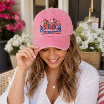 Woman smiling outdoors wearing a pink washed baseball cap with embroidered patriotic floral America design