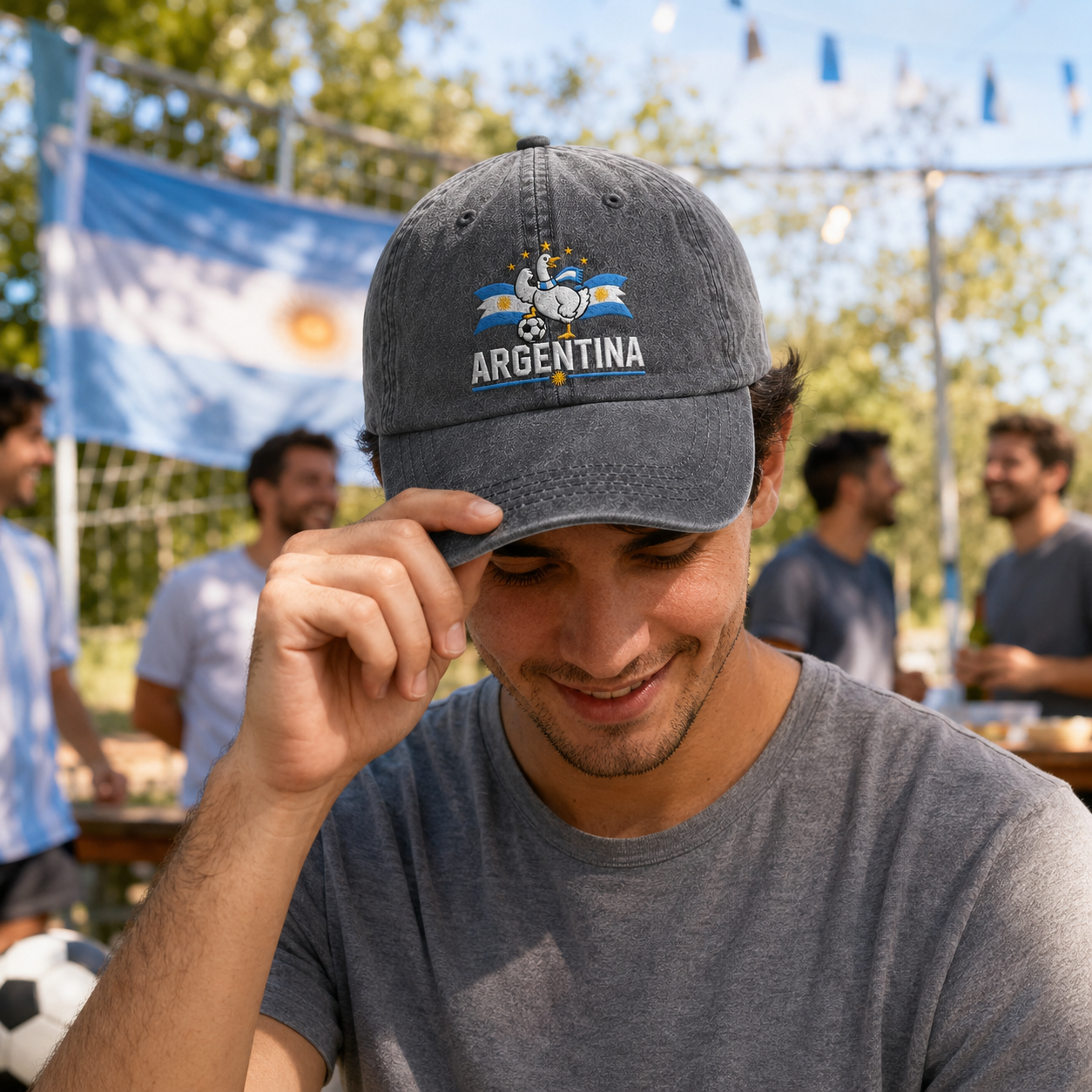 Man adjusting his cap at an outdoor sports party wearing a grey washed baseball cap with an embroidered Argentina soccer goose design