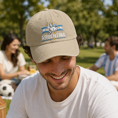 Man smiling at a park picnic wearing a sand washed baseball cap with an embroidered Argentina soccer goose design