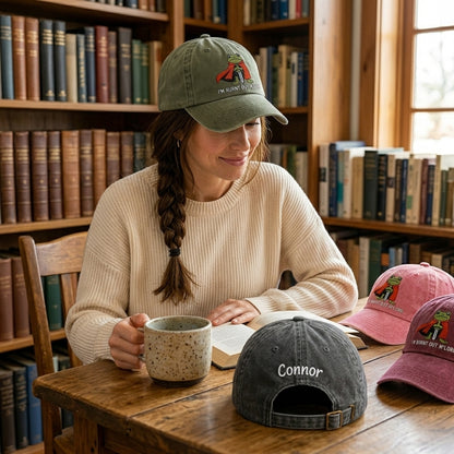 Woman reading a book in a library with hats on a table in front of her.