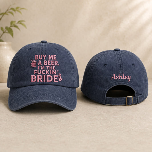 Two navy blue baseball caps with pink text on a beige surface.