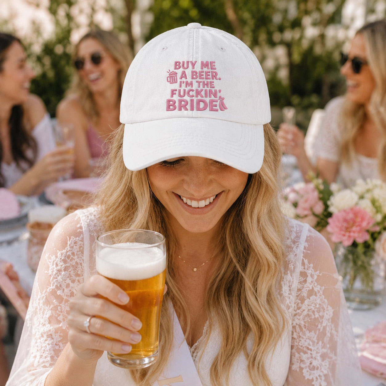 Woman wearing a cap with text and holding a beer at a social gathering.