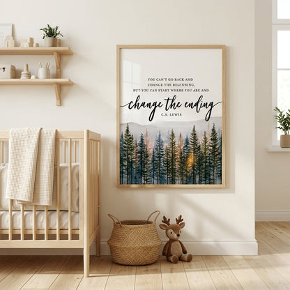 A framed wall art print with an inspirational quote and a forest illustration hangs on a cream wall in a styled nursery. The print is shown in a light wood frame, with a crib, woven basket, and stuffed toy visible in the room.