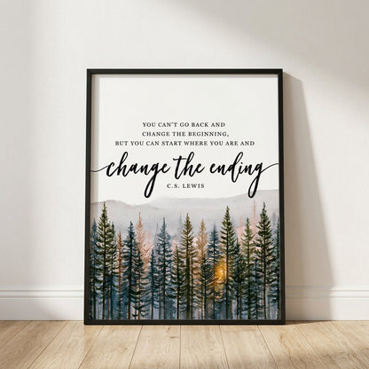 A framed art print leaning against a white wall on a light wood floor. The print features a black frame, a quote by C.
