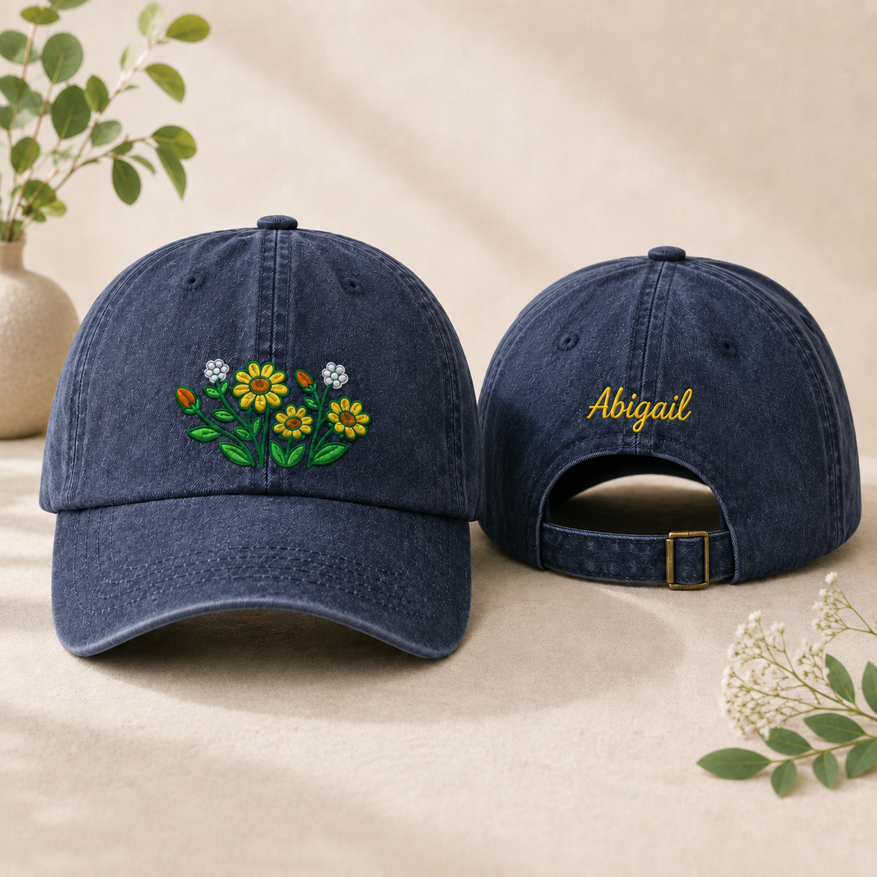 Front and back view of a navy washed baseball cap with embroidered daisy wildflower design and custom name text
