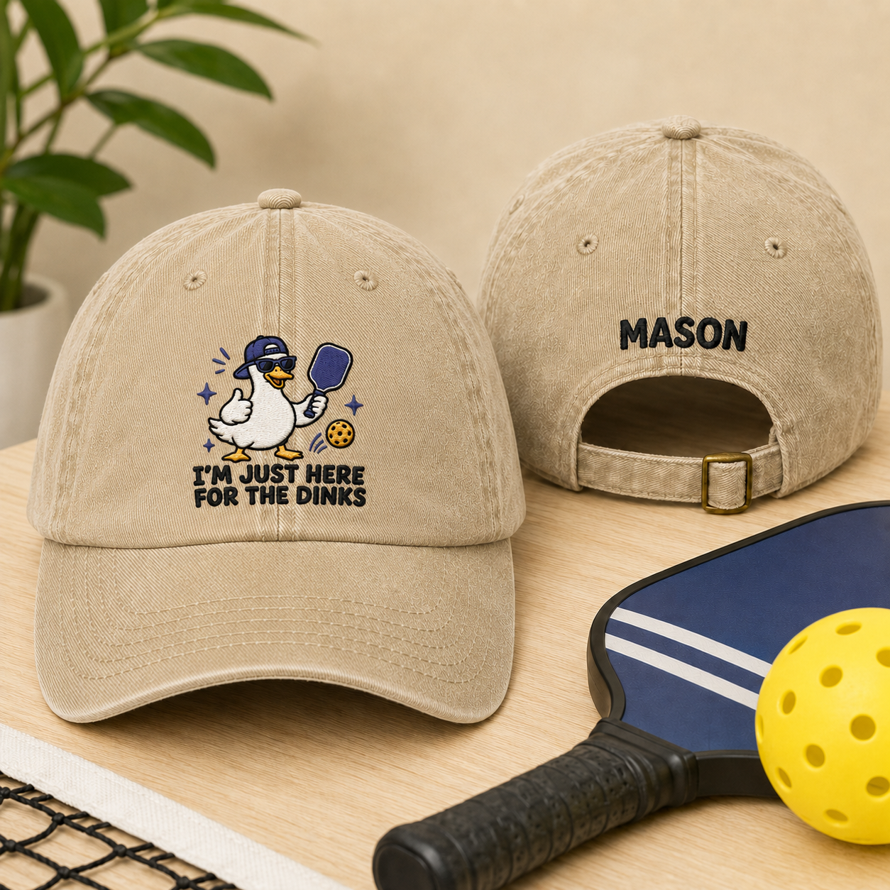 Front and back view of a sand washed cotton baseball cap featuring an embroidered cartoon duck pickleball design and custom name Mason text