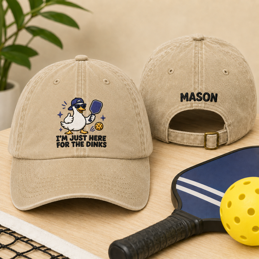 Front and back view of a sand washed cotton baseball cap featuring an embroidered cartoon duck pickleball design and custom name Mason text