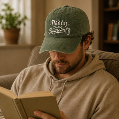 Man wearing a green cap with text and a logo, reading a book indoors.