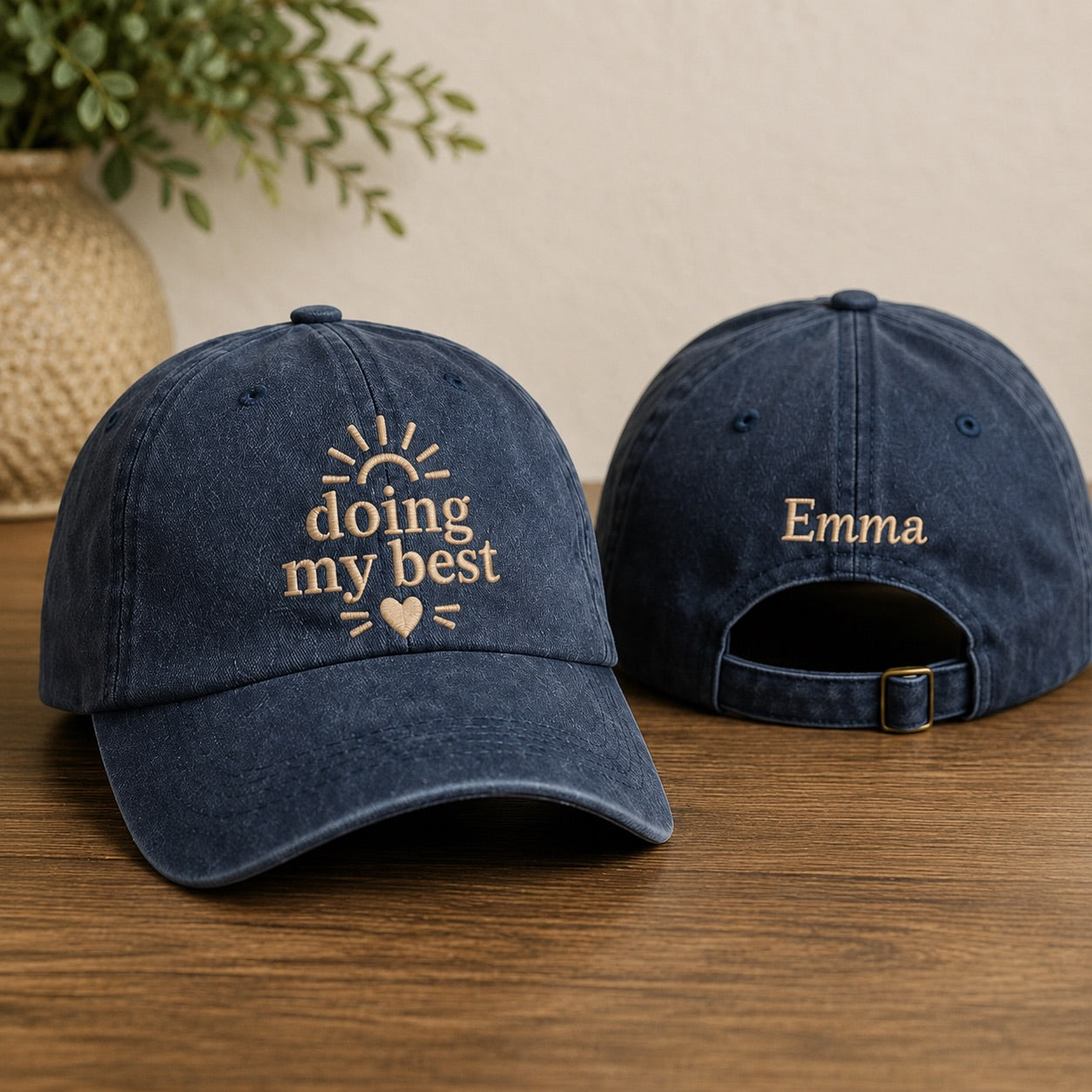 Two navy blue baseball caps with embroidered text on a wooden surface.