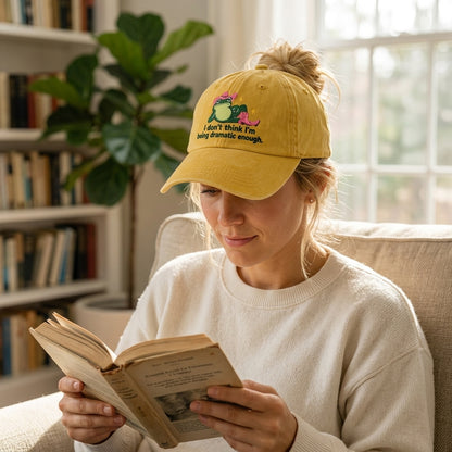 Woman wearing a yellow cap with text, reading a book in a cozy room.