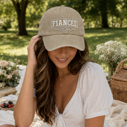Woman at a picnic wearing a sand washed cotton baseball cap with white embroidered fiancee est 2026 text