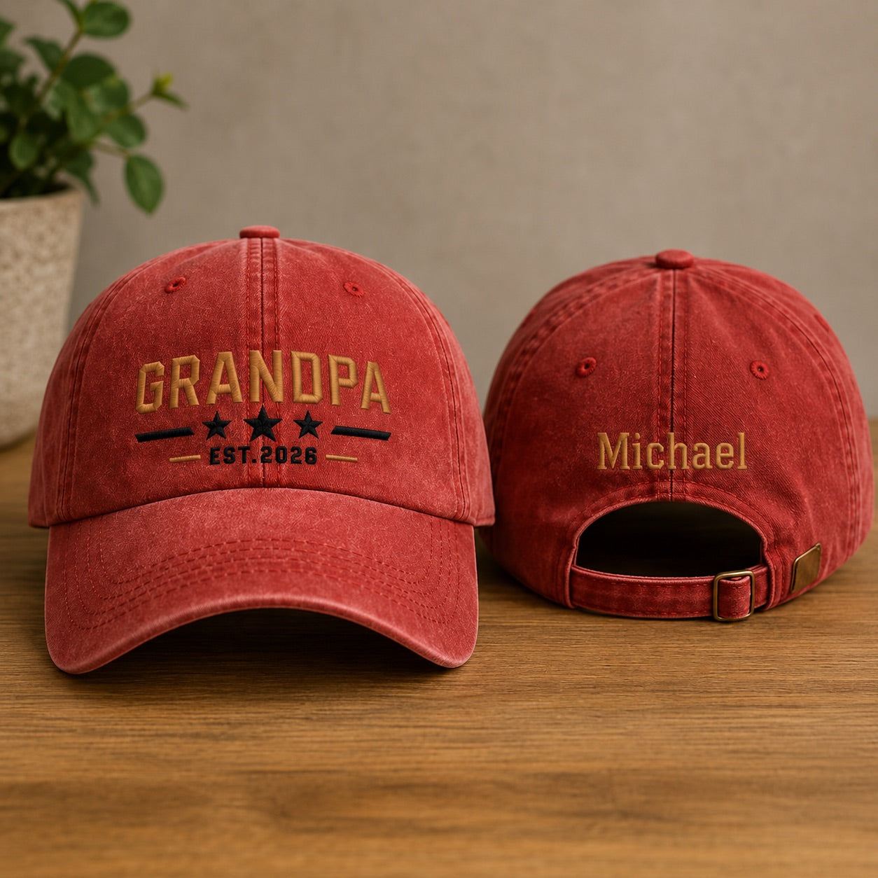 Two red baseball caps with embroidered text on a wooden surface.
