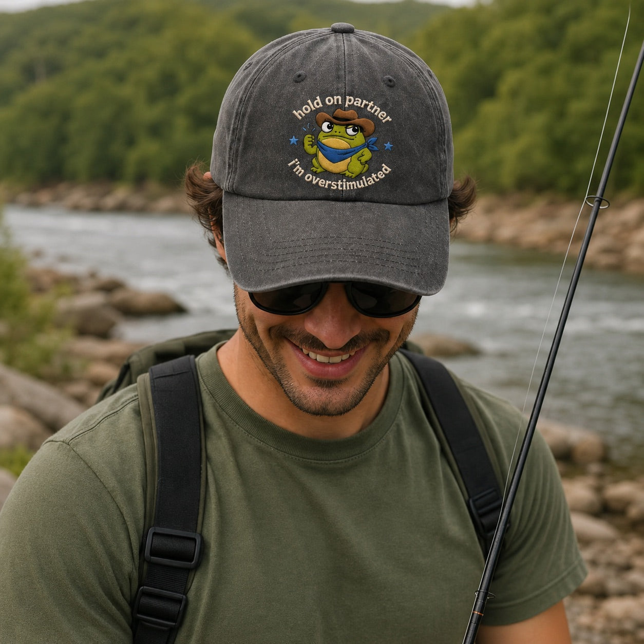 Man wearing a cap with a humorous design by a river