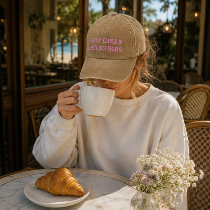 Person drinking from a mug with a cap and a croissant on a table.