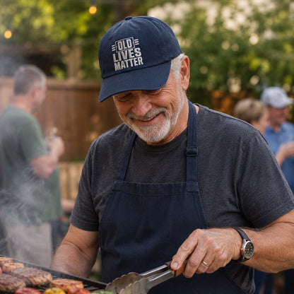 Man grilling outdoors wearing a cap with 'Old Lives Matter' text