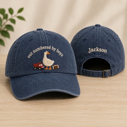 Two blue denim caps with embroidered designs on a wooden surface.