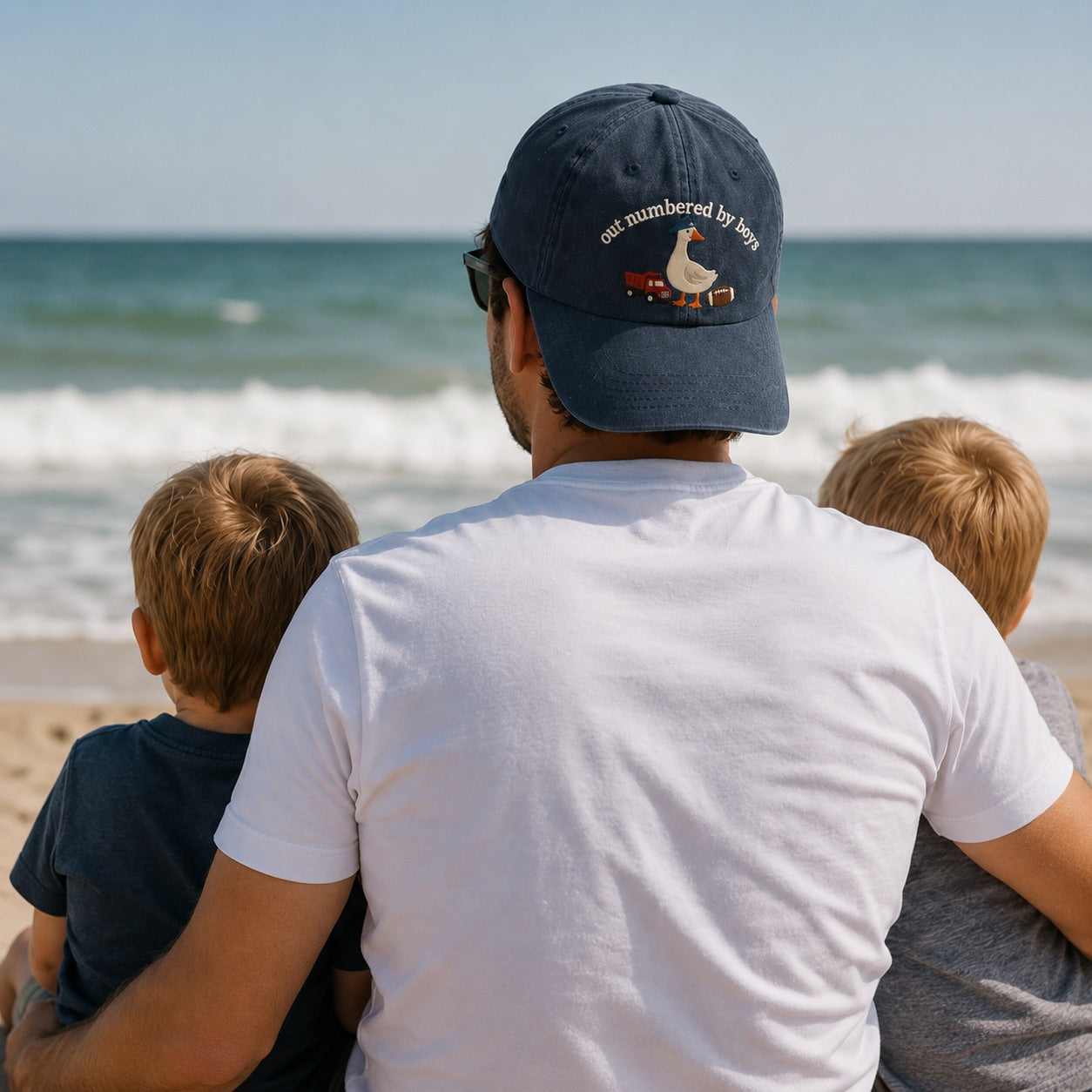 Man and two children sitting on a beach, looking at the ocean.