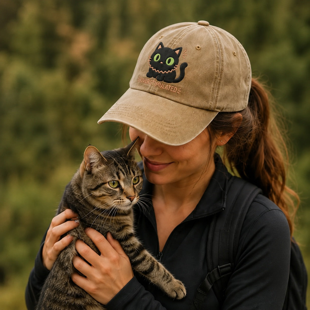 Woman holding a cat wearing a cap with a cat design outdoors