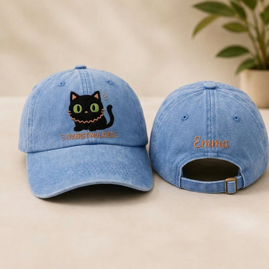 Two denim baseball caps with embroidered designs on a beige surface.