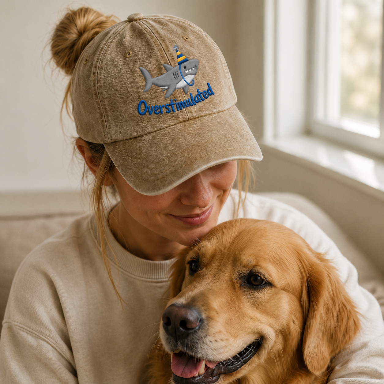Person wearing a cap with a shark design and 'Overstimulated' text, sitting with a dog indoors.
