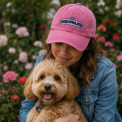 Woman wearing a pink 'Overstimulated' cap with a dog in front of flowers