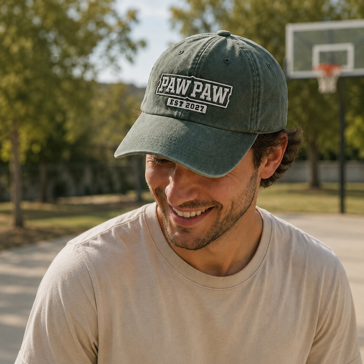 Man wearing a green cap with 'PAW PAW EST 2021' logo on a basketball court.
