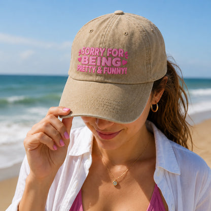 Woman on a beach wearing a cap with text, with ocean and sky in the background