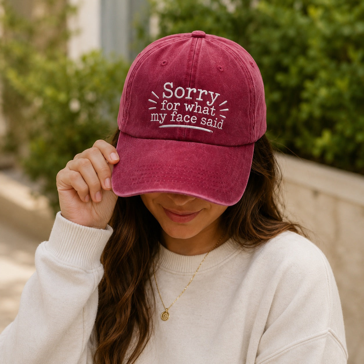 Person wearing a maroon cap with text, outdoors.