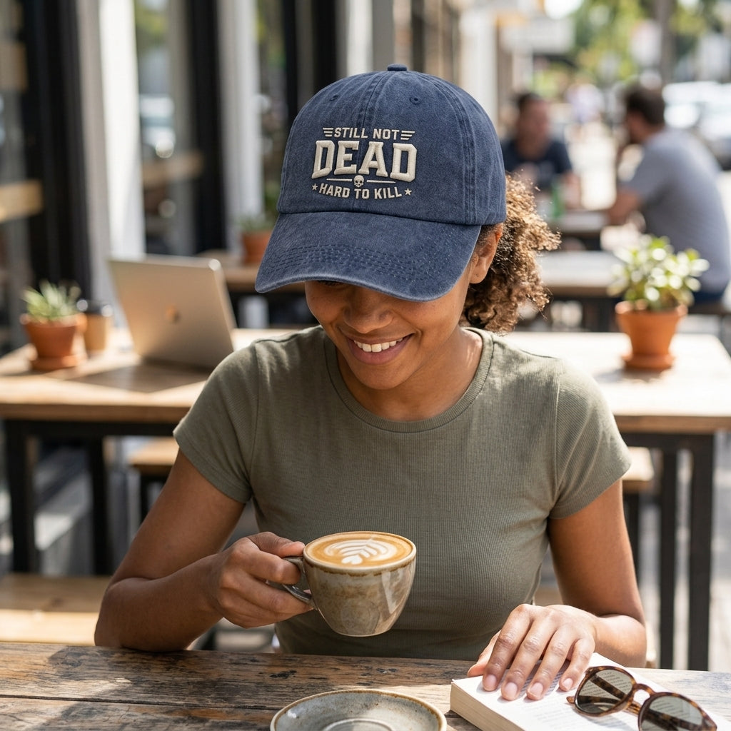 Person wearing a cap with text, holding a coffee cup in an outdoor cafe setting