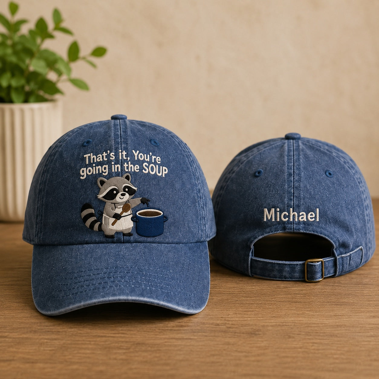 Blue denim cap with raccoon design and text on a wooden surface