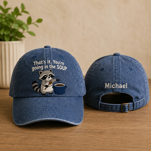 Blue denim cap with raccoon design and text on a wooden surface