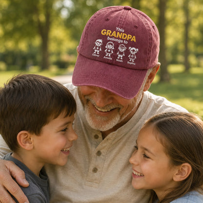 Man wearing a maroon cap with text and children's drawings, sitting with two children outdoors.