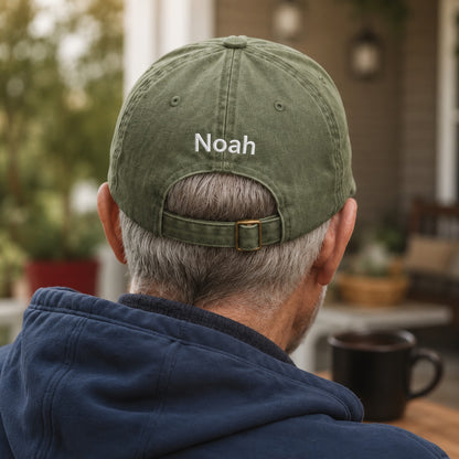 Person wearing a green cap with 'Noah' on the back, sitting outdoors.
