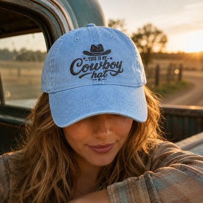 Light blue washed baseball cap with custom cowboy hat embroidery worn by a woman next to a truck