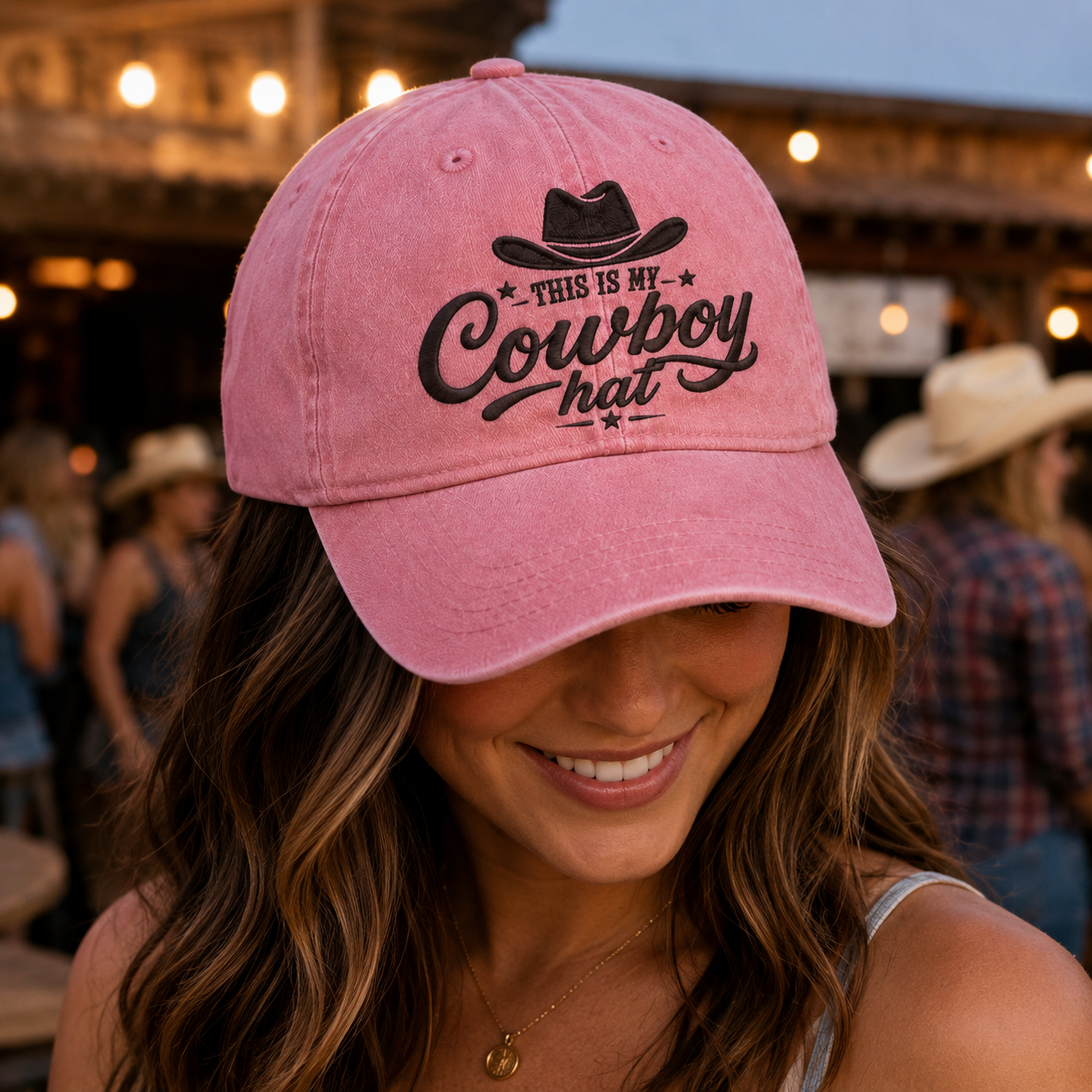 Pink washed cotton baseball cap with black embroidered cowboy hat design worn by a woman at a country bar