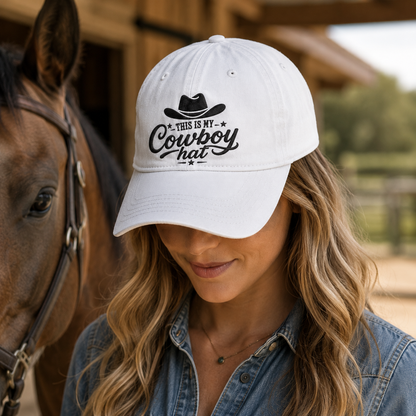 White washed baseball cap with embroidered black cowboy design worn by a woman standing next to a horse