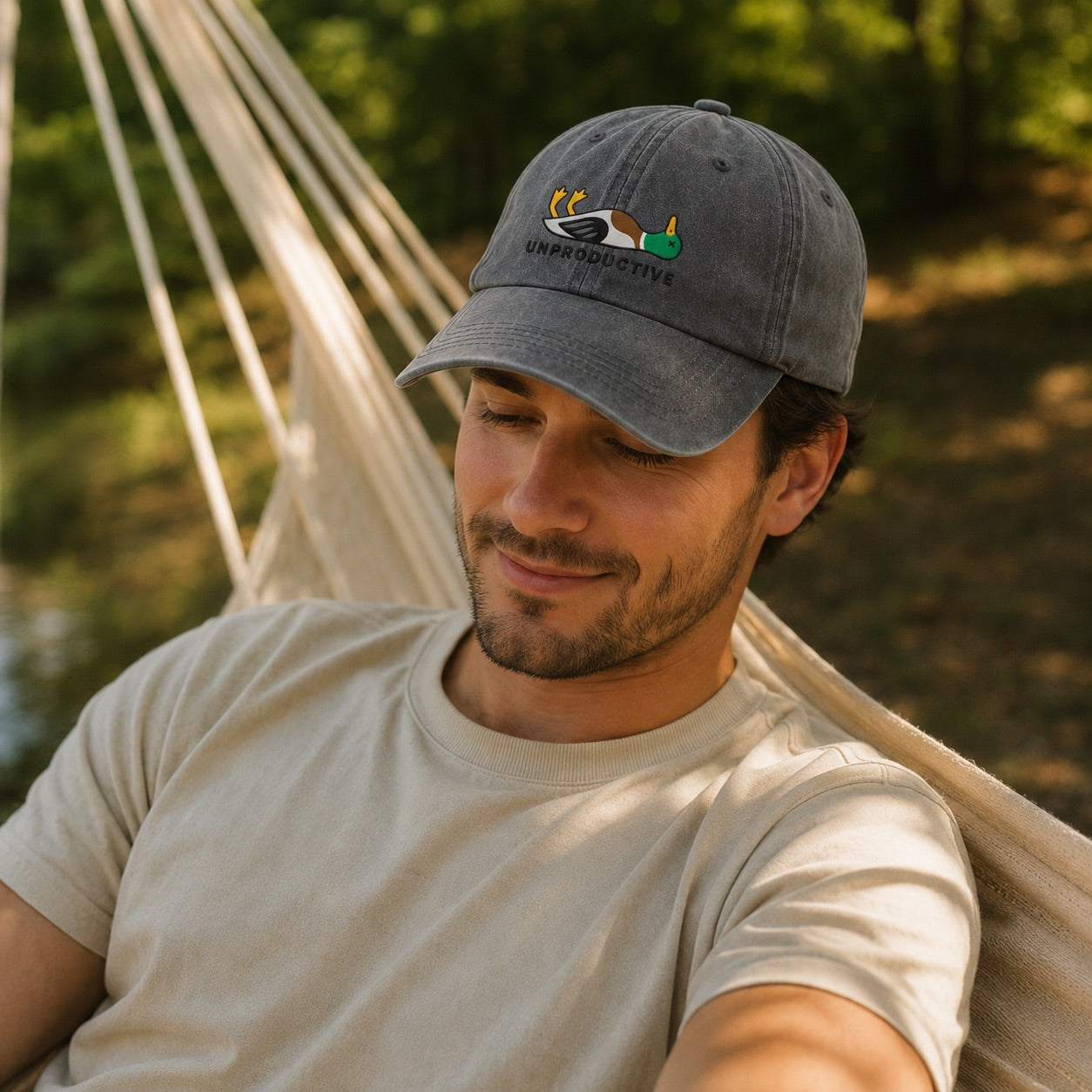 Man wearing a cap with a logo, sitting in a hammock outdoors.