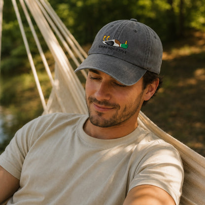 Man wearing a cap with a logo, sitting in a hammock outdoors.