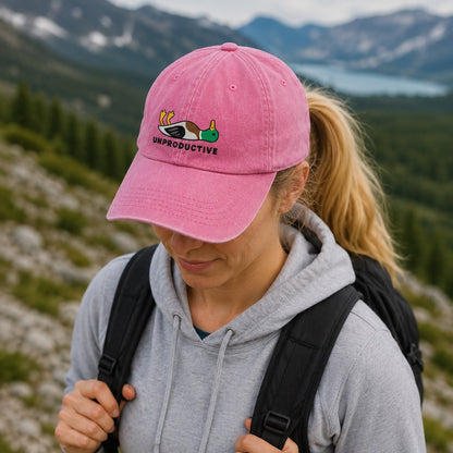 Person wearing a pink cap with a humorous design in a mountainous landscape