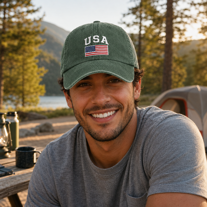 Man smiling at a campsite wearing an army green washed baseball cap with an embroidered USA flag design