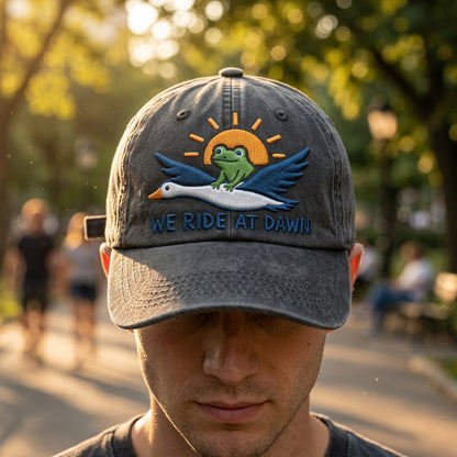 Person wearing a cap with a logo and text 'We Ride at Dawn' in an outdoor setting.
