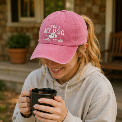 Woman wearing a pink cap with text and holding a mug outdoors.